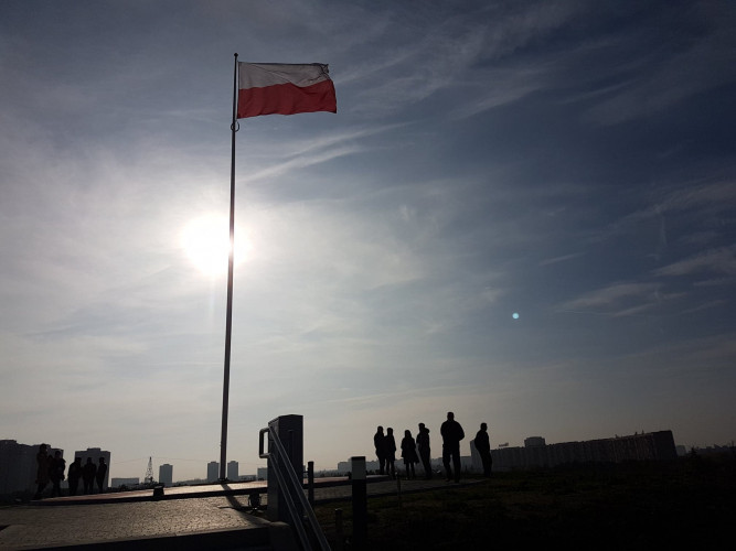 Ludzie na szczycie kopca, maszt z flagą Ludzie na szczycie kopca, maszt z flagą